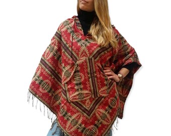 May include: A red, black, and beige hooded poncho with a geometric pattern and fringe. The poncho has a pocket on the front.