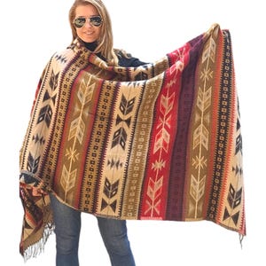 May include: A large, woven shawl with a colourful geometric pattern featuring arrows and stripes in shades of brown, beige, red, and black. The shawl has fringe on the edges.
