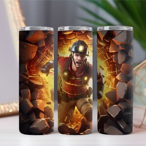 Puede incluir: Un vaso de acero inoxidable con un gráfico de un hombre con uniforme de bombero rompiendo una pared de rocas. El hombre lleva un casco con una linterna frontal y tiene una expresión decidida en su rostro. El fondo es de color naranja y amarillo fuego.