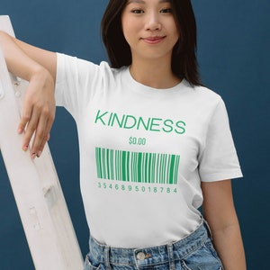 Peut inclure: T-shirt blanc avec le mot "KINDNESS" imprimé en lettres vertes et un code-barres vert en dessous. Le prix est indiqué à 0,00 €.