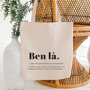May include: A beige tote bag with black text that reads "Ben là." The text is defined as "1. value of argument (but not very convincing). 2. Used to show exasperation, indignation, in the context of an injustice."