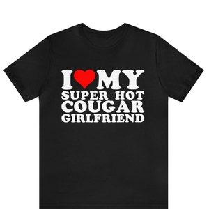 Puede incluir: Camiseta negra con texto blanco que dice "I ♥ MY SUPER HOT COUGAR GIRLFRIEND".