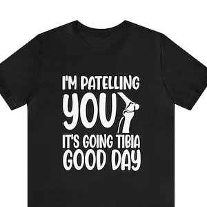 May include: Black t-shirt with a white graphic of a knee joint and the text "I'm patelling you it's going tibia good day."