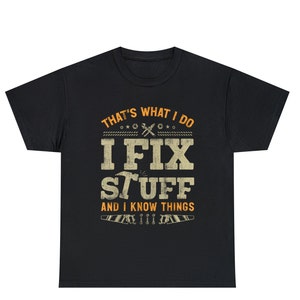 May include: Black t-shirt with a distressed white graphic that says "That's what I do I fix stuff and I know things". The graphic is surrounded by small orange tools.