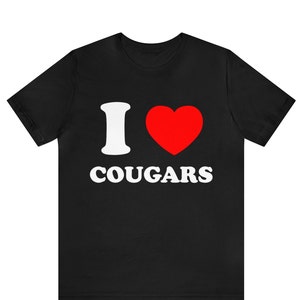 Puede incluir: Camiseta negra con texto blanco que dice "I love Cougars" y un corazón rojo.
