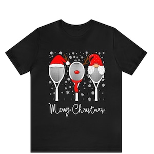 May include: Black t-shirt with a Christmas-themed design featuring three tennis rackets with Santa hats and the text "Merry Christmas".