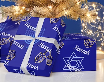 May include: Blue wrapping paper with a gold Star of David, menorah, and dreidels. The paper is personalized with the name "Hannah".