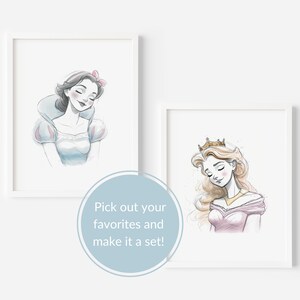May include: Two framed illustrations of Disney princesses. The first illustration is of Snow White with a pink bow in her hair. The second illustration is of a princess with long blonde hair wearing a crown and a pink dress.