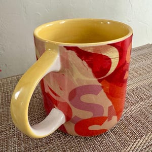 May include: A set of three ceramic mugs with a speckled, matte finish. The mugs are in shades of cream, light gray, and dark gray. Each mug has a simple, minimalist design, perfect for coffee or tea.