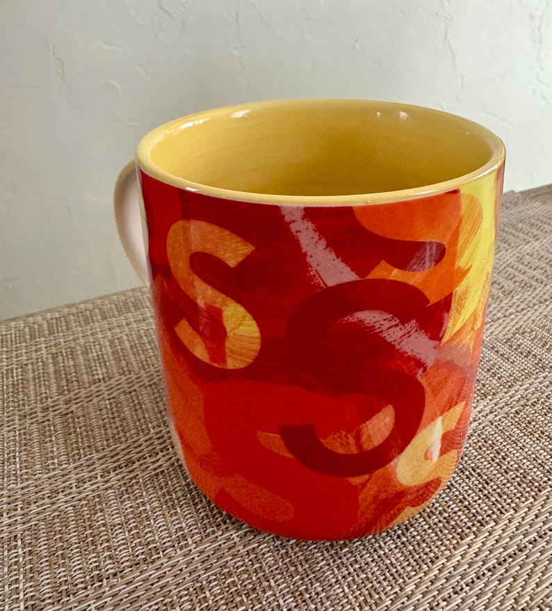 May include: A white ceramic mug with a black handle and the text "But First, Coffee" in a black, bold font. The mug is on a white surface. The mug is 4 inches tall.
