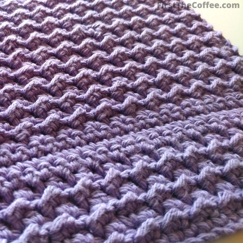May include: Purple crocheted dishcloth with a textured pattern.