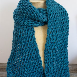 May include: A teal blue knitted scarf with a lacy pattern. The scarf is draped over a fabric-covered mannequin.