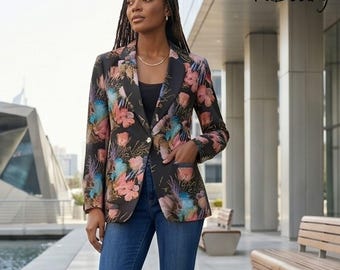 May include: A black blazer featuring a vibrant floral print in shades of pink, blue, and yellow, paired with a black top, blue denim jeans, and black high-heeled pumps. The blazer has a single button closure and two front pockets.
