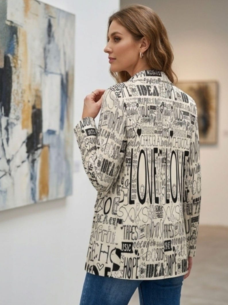 Puede incluir: Blazer color crema con un dise&ntilde;o de texto negro, incluyendo la palabra "LOVE" en letras grandes. El blazer se lleva con vaqueros azules. El fondo incluye arte abstracto y un entorno de galer&iacute;a.