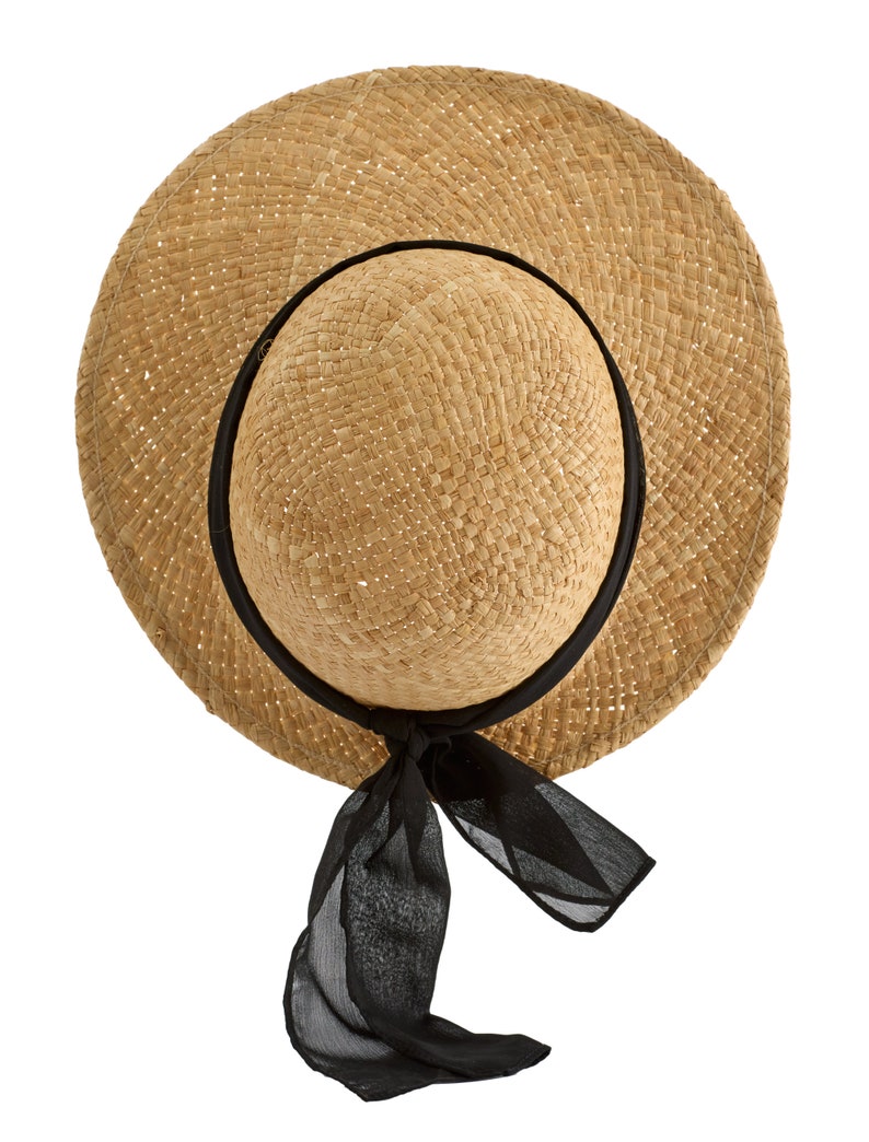 May include: A straw hat with a wide brim and a black ribbon tied at the back. The hat is made of woven straw and has a natural color.