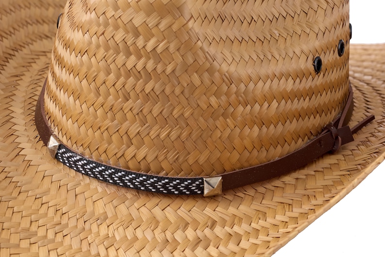 May include: A straw cowboy hat with a brown leather band and a black and white patterned band. The hat has a woven texture and a pointed crown.