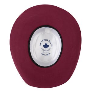 K&ouml;nnte beinhalten: Die Innenseite eines burgunderfarbenen Filzhutes mit einem schwarzen Band und einem wei&szlig;en Etikett mit der Aufschrift "Ontario Hats, Made in Canada, OAF 6619, Since 2021".