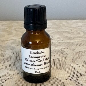 May include: A small amber glass bottle with a black cap, labeled "Headache Therapeutic Diffuser/Cool Mist Aromatherapy Blend 100% pure therapeutic grade oils 15mL".
