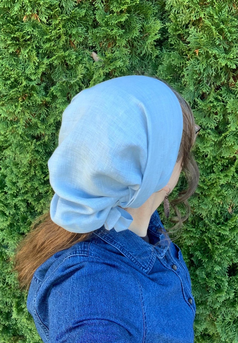 Pode incluir: Um len&ccedil;o de cabe&ccedil;a azul-claro feito de um tecido entrela&ccedil;ado com textura vis&iacute;vel. O len&ccedil;o &eacute; atado na parte de tr&aacute;s com um n&oacute; e cai suavemente sobre a cabe&ccedil;a, oferecendo uma cobertura total com um aspeto macio e franzido.
