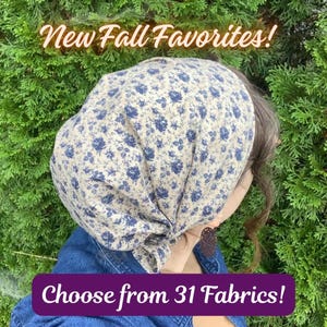 May include: A headscarf featuring a beige fabric with a dark blue floral pattern. The text "New Fall Favorites!" appears at the top, and the text "Choose from 31 Fabrics!" is displayed in a purple banner at the bottom of the image.
