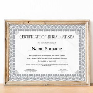Könnte beinhalten: Ein gerahmtes Zertifikat für die Seebestattung mit einem grauen und weißen Design. Das Zertifikat lautet "CERTIFICATE OF BURIAL AT SEA" und enthält den Text "The cremated remains of: Name Surname were respectfully scattered on the Pacific Ocean in accordance with the laws of the State of California On the 18th of April, 2027".