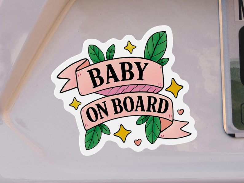 Baby On Board magnet with pink ribbon, stars, and green leaves on white car