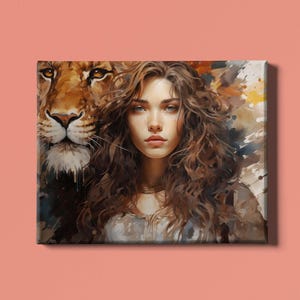 Op de afbeelding: Canvas print met een aquarel schilderij van een vrouw met lang, bruin krullend haar en een leeuw. Het gezicht van de leeuw is gedeeltelijk zichtbaar achter de vrouw. Het kunstwerk heeft een warm kleurenpalet met tinten bruin, goud en blauw.