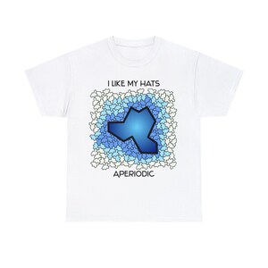 May include: White t-shirt with a blue and white graphic design. The graphic features a blue shape surrounded by white and blue stars. The text "I LIKE MY HATS" and "APERIODIC" are printed on the shirt.