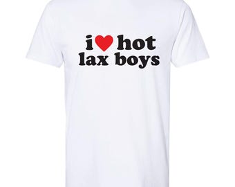 May include: A white short-sleeved t-shirt featuring the black text "i" followed by a red heart symbol and the black text "hot lax boys" printed in a bold, rounded font across the center of the chest area.