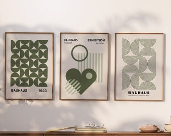 May include: Three framed prints with geometric designs in shades of green. The prints are titled "Bauhaus" and feature the years 1923 and 1923. The prints are hanging on a white wall.