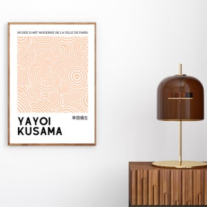 May include: A poster featuring an abstract peach-coloured pattern of circles and swirls. The text "MUSE&Eacute; D'ART MODERNE DE LA VILLE DE PARIS" is at the top of the poster. The text "YAYOI KUSAMA" is at the bottom of the poster, with the Japanese text "草間彌生" to the right.