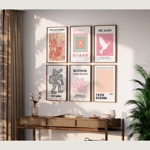 May include: A gallery wall featuring nine framed art prints by various artists. The prints include works by William Morris, Bauhaus, Picasso, Matisse, Keith Haring, and Yayoi Kusama. The prints are arranged in a grid pattern on a white wall.