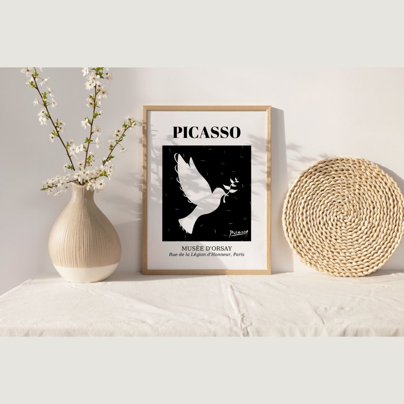 May include: Black and white poster with a white dove holding an olive branch in its beak. The poster has the text "PICASSO" at the top and "MUS&Eacute;E D'ORSAY" at the bottom. The text "Rue de la L&eacute;gion d'Honneur, Paris" is below the museum name.