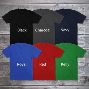 Pu&ograve; includere: Sei t-shirt di diversi colori: nero, antracite, blu navy, blu reale, rosso e verde kelly. Ogni t-shirt ha un design semplice ed &egrave; posizionata su una superficie di legno.