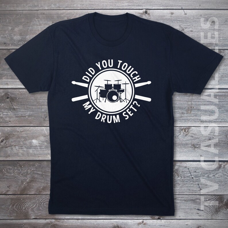 Pu&ograve; includere: Una t-shirt blu navy con una grafica bianca di una batteria e il testo "Did you touch my drum set?"