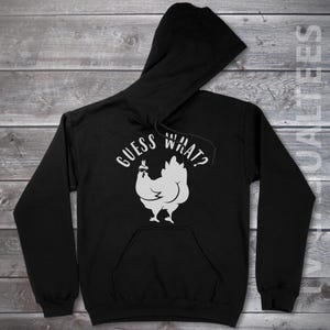 May include: Black hooded sweatshirt with a white graphic of a chicken wearing sunglasses and the text "GUESS WHAT?"