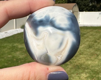May include: A smooth, white and gray agate stone with swirling patterns. The stone is polished and has a glossy finish.