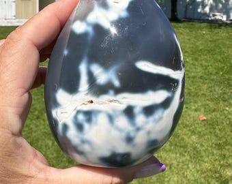 May include: A white and black agate egg with a smooth, polished surface. The egg has a unique pattern of white and black swirls and veins.
