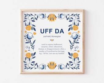 May include: A framed print with a white background and a blue and yellow floral border. The text "UFF DA (oof-dah) Norwegian" is in the center of the print. The text below defines the word as a Norwegian expression used to express bafflement, surprise, relief, exhaustion, dismay, or disappointment, often a marker of Scandinavian heritage. An example is given: "uff da, Lars ate my lutefisk."