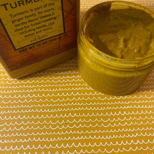 Puede incluir: Un tarro de vidrio lleno de especias de cúrcuma molida. El tarro está sobre una superficie con un patrón amarillo y blanco. La etiqueta del tarro dice "Cúrcuma molida" e incluye información sobre la especia, incluyendo su origen y usos. Peso neto 12 oz (340 g).