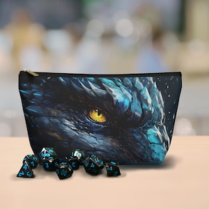 Könnte beinhalten: Eine schwarze Reißverschlusstasche mit einem blauen und weißen Drachenaugen-Druck. Die Tasche ist offen und enthält zehn schwarze Würfel mit blauen Zahlen.