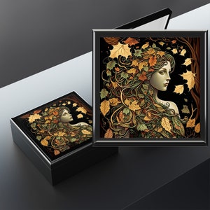 May include: A black wooden box with a hinged lid. The lid features a colourful illustration of a woman with long hair adorned with autumn leaves. The background is a dark forest scene.