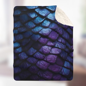 May include: A soft, plush fleece blanket with a dark blue and purple iridescent scale pattern. The blanket is perfect for cuddling up on the couch or in bed.