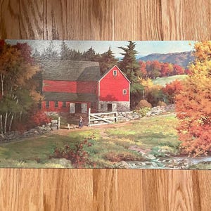 May include: A rectangular painting depicts a red barn with a gray roof, set against a backdrop of autumn foliage. A person walks a dog along a stone wall. The artwork showcases a serene rural landscape with a stream and colorful trees.
