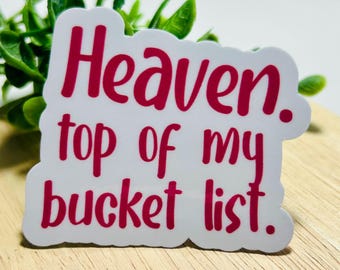 Może przedstawiać: Biała, wycinana naklejka z falistym brzegiem, zawierająca napis "Heaven. top of my bucket list." wydrukowany pogrubioną, ciemnoróżową czcionką imitującą pismo odręczne. Naklejka ma gładkie, błyszczące wykończenie i podąża za konturami tekstu.