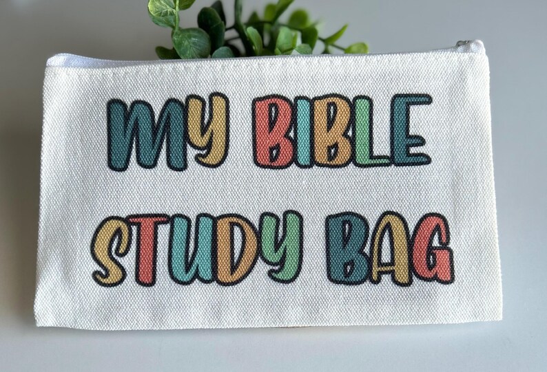 Pu&ograve; includere: Una pochette con cerniera in tela bianca con il testo MY BIBLE STUDY BAG stampato in un carattere multicolore di ispirazione retr&ograve;. Le lettere si alternano tra tonalit&agrave; tenui di blu, giallo, rosso e verde, ciascuna con un bordo nero.