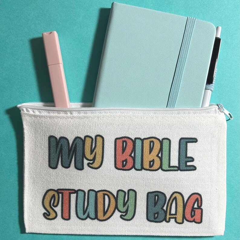 Pu&ograve; includere: Una pochette con cerniera in tela bianca con la scritta "MY BIBLE STUDY BAG" stampata in lettere colorate e arrotondate. All'interno della pochette si trovano un taccuino azzurro, un evidenziatore rosa pallido e una penna bianca e nera su sfondo verde acqua.
