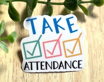 Może przedstawiać: Biała naklejka z napisem "TAKE ATTENDANCE" w kolorze niebieskim i czarnym. Naklejka zawiera trzy pola wyboru w kolorze zielonym, różowym i pomarańczowym, każde ze znakiem wyboru w środku. Naklejka znajduje się na drewnianej powierzchni z zielonymi liśćmi.