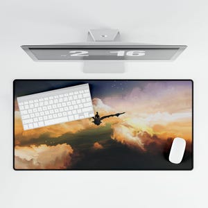 Puede incluir: Alfombrilla de ratón rectangular negra con un diseño de puesta de sol colorido que representa a una persona montada en un dragón. Un teclado y un ratón blancos están sobre la alfombrilla. Un monitor de ordenador está encima.