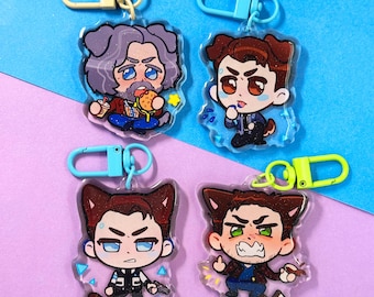 May include: Four clear acrylic keychains with cartoon character designs. Each keychain features a different character with a unique expression and pose. The keychains have colorful accents and metal clasps for attachment. The characters are depicted in a chibi style.